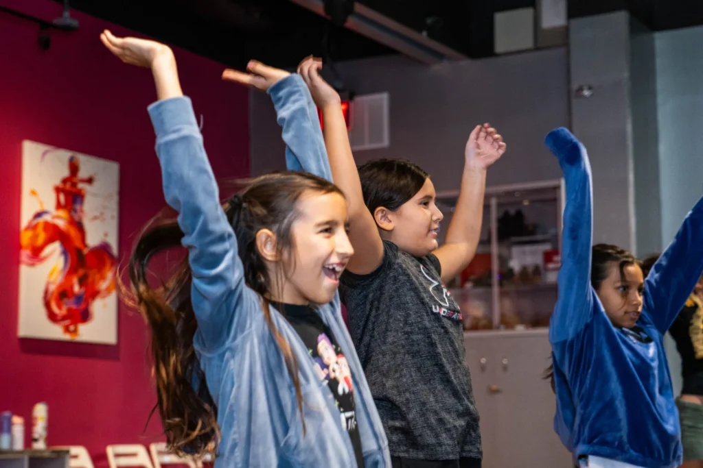 Smiling kids stretching their arms high during a dance class