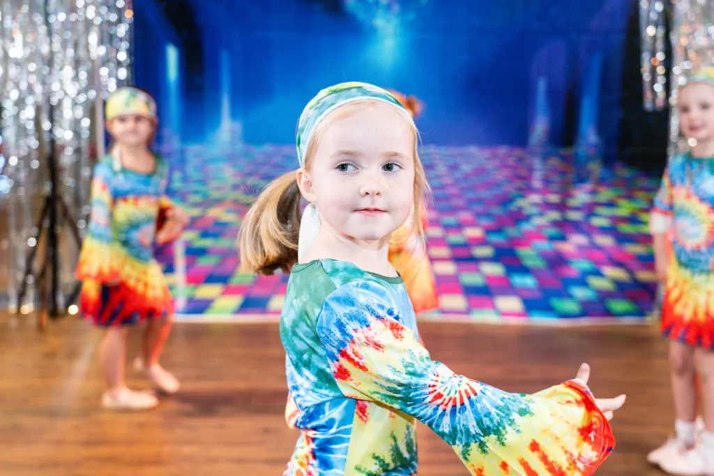 Young dancer mid-turn in a tie-dye costume on stage